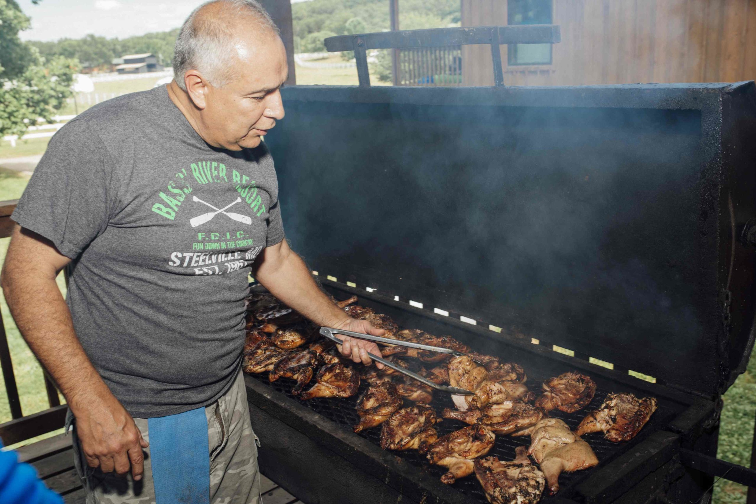Man grilling chicken on a large grill