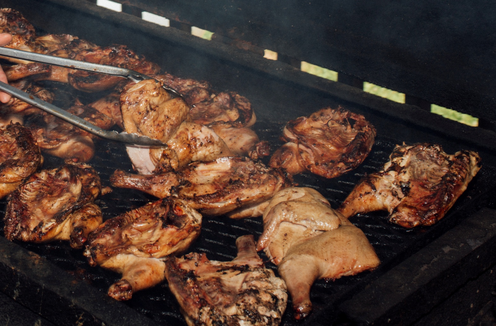 Man grilling chicken on a large grill