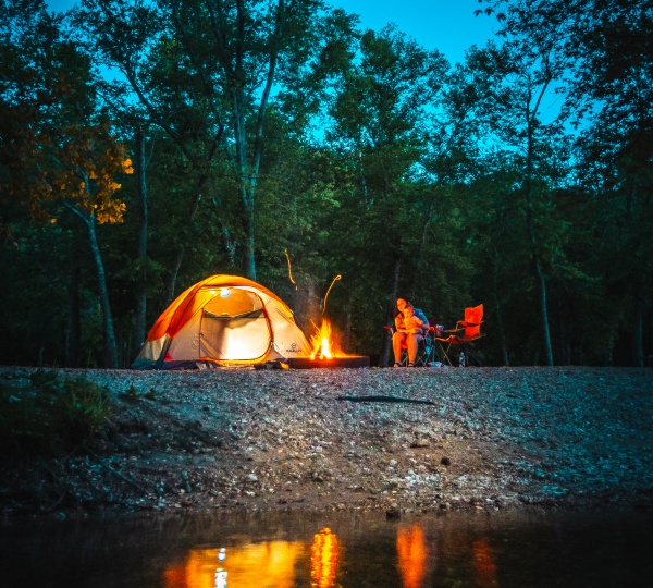 Camping at night, a woman and her daughter sit around a campfire.