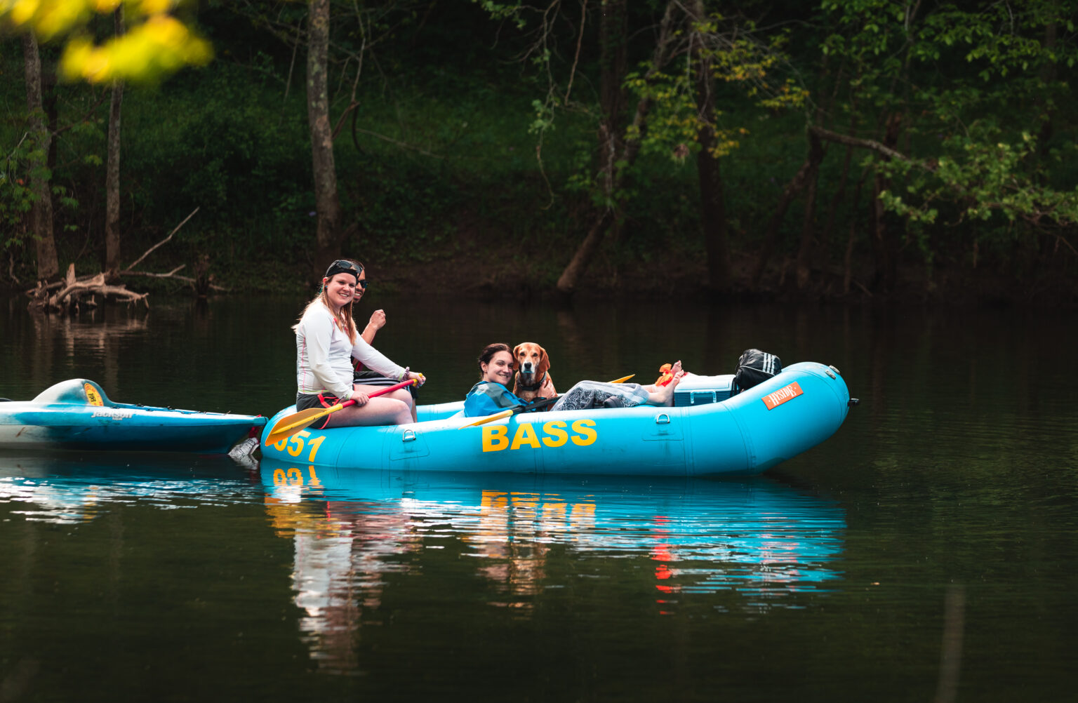 A group of people and their dog enjoying a scenic raft trip on the crystal clear Courtois River.